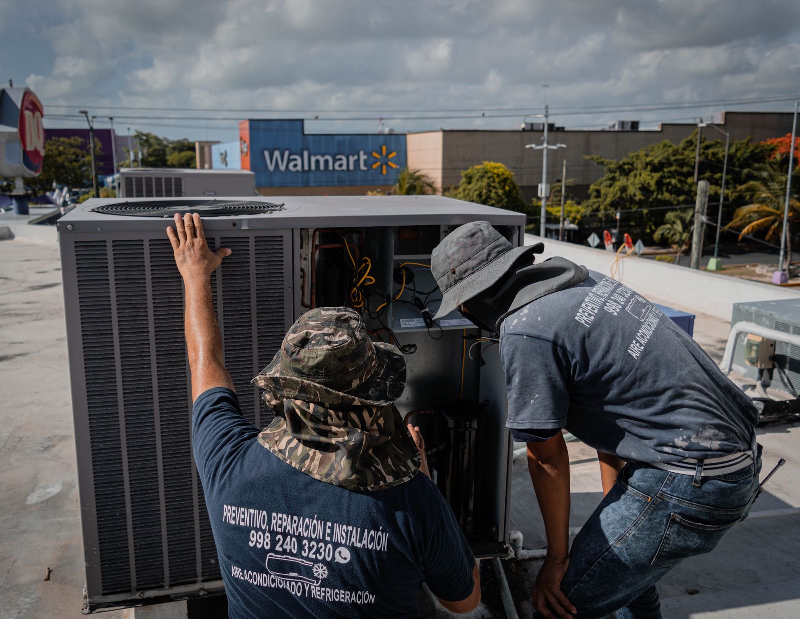 Technicians repairing a commercial rooftop HVAC unit